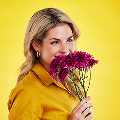 Image showing Portrait, smile and woman smelling flowers in studio isolated on a yellow background. Floral, bouquet and happiness of person sniffing or female model with scent of natural plants and dahlia aroma.