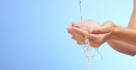 Image showing Water splash, woman or cleaning hands in studio on blue background for wellness or skincare hydration. Mockup space banner, palm or girl with liquid splash hand wash in hygiene or bacteria prevention