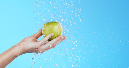 Image showing Water, apple washing and hands with fruit for wellness, healthcare and nutrition self care. Healthy food, green and natural skincare with hand cleaning health snack for diet in blue background studio