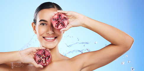 Image showing Pomegranate, portrait and water splash of woman, beauty and wellness on blue background banner. Happy model, shower and healthy fruits for natural benefits, detox nutrition and skincare dermatology