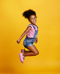 Image showing Excited, jump and happy girl child jumping in happiness, joy and smile while isolated in a studio yellow background. Energy, celebrate and kid in the air due to winning, celebrating and succuss