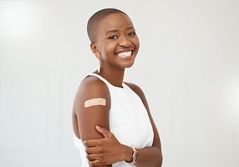 Image showing Black woman, portrait and covid plaster on arm in studio for injection with medical insurance. Portrait of African female happy on a white background with healthcare vaccine, safety and mockup space