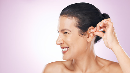 Image showing Woman, cotton and clean ear in studio with happiness for wellness, health and pink background. Model hand, self care and cleaning for hygiene, earwax and natural product with smile by background