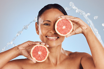 Image showing Skincare, portrait and woman with a grapefruit in studio for a natural, beauty and organic face routine. Cosmetic, water splash and mature female model with a citrus fruit isolated by blue background