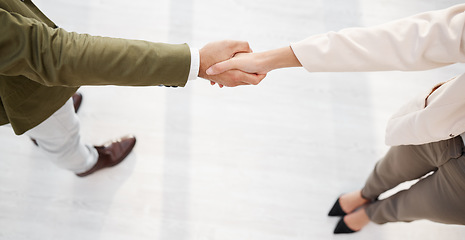 Image showing Business people, handshake and partnership in meeting above for greeting, b2b or introduction at the office. Businessman and woman shaking hands in agreement, deal or collaboration at the workplace