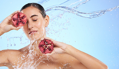 Image showing Pomegranate, face and water splash of woman, beauty and wellness on studio blue background. Calm model, shower and healthy fruits for natural benefits, detox vegan nutrition and skincare dermatology