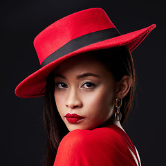 Image showing Portrait, red and fashion with a woman on a dark background in studio rich or wealthy style. Face, elegant and classy with an attractive young female model posing in modern designer clothes