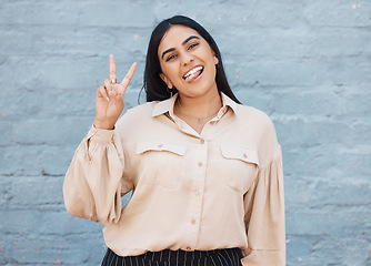 Image showing Business woman, portrait and tongue out with peace sign against a gray wall background. Happy and goofy female face smiling showing peaceful hand emoji, sign or gesture with funny or silly expression