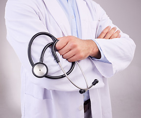 Image showing Doctor, hands and stethoscope of man with arms crossed in healthcare cardiology against gray studio background. Closeup of male medical professional holding tool for checkup or heart rate monitoring