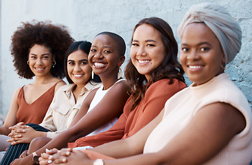 Image showing Portrait, diversity and a group of happy businesswomen sitting in a line as coworkers against a wall outside in the city. Businesspeople smiling while sitting outdoors as woman employee colleagues