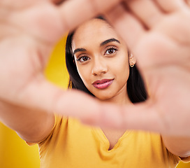 Image showing Hands, frame and portrait of a woman with perspective isolated on a yellow background in a studio. Looking, creative and a girl with focus on face, shape and showing creativity on a backdrop