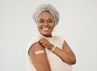 Image showing Black woman, smile and covid plaster on arm in studio for injection with medical insurance. Portrait of African female happy on a white background with vaccine, safety compliance and mockup space