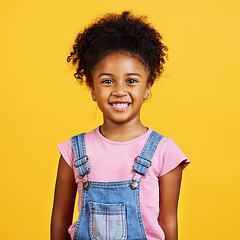 Image showing Studio portrait mixed race girl looking standing alone isolated against a yellow background. Cute hispanic child posing inside. Happy and cute kid smiling and looking carefree in casual clothes