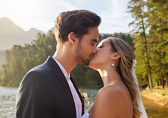 Image showing Love, wedding and kiss with a newlywed couple by a lake outdoor in celebration of marriage or romance. Water, summer and a bride and groom kissing while bonding together in tradition after ceremony