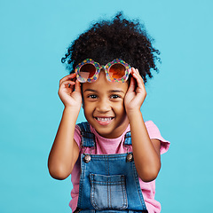 Image showing Portrait, funky glasses and girl with smile, excited and cheerful against a blue studio background. Face, female child and young person with cute eyewear, trendy and happiness with joy or accessory