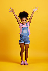 Image showing Studio, portrait and excited child with hands up and a smile on face on yellow background. Happy young girl kid model with happiness, carefree and positive attitude for surprise sale announcement