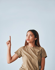 Image showing Idea, thinking and a pointing woman with space isolated on a white background in a studio. Direction, mockup and a girl gesturing for a plan, contemplation or a decision on a backdrop or wall