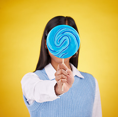 Image showing cover, lollipop and candy with woman in studio for sweets, colorful snack and food. Treats, dessert and sugar confectionery with female isolated on yellow background for diet, eating and hiding