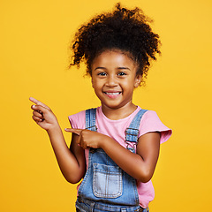 Image showing Portrait, studio and happy child pointing hand at space with a smile on face on yellow background. Young girl kid with happiness, carefree and positive attitude to show product placement mockup deal