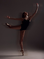 Image showing Flexibility, dance and woman in the dark for ballet isolated on a black background in a studio. Creative, elegant and dancer dancing for a theater performance, rehearsal or ballerina movement