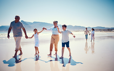 Image showing Beach, family holding hands and grandparents with children playing and walking on ocean sand together. Fun, vacation and senior man and woman with kids bonding, quality time and summer walk in nature