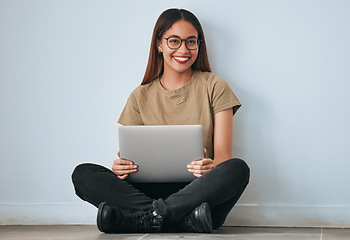 Image showing Portrait, smile and student woman with laptop in home for studying, learning or education. Technology, computer and happy female sitting on floor with pc for research on wall background for mockup.