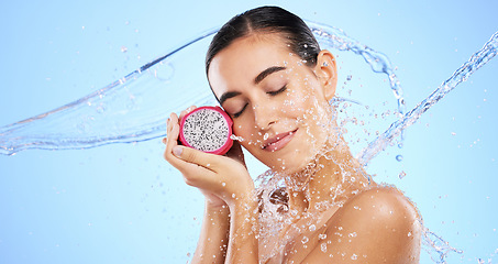 Image showing Dragon fruit, water splash or woman with beauty in studio on blue background for healthcare or vegan diet. Eyes closed, skincare wellness or healthy girl model face with fruits or vitamin c to detox