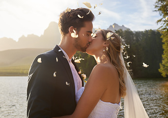 Image showing Love, wedding and confetti with a couple kissing by a lake outdoor in celebration of a marriage for romance. Water, summer or kiss with a bride and groom bonding together in tradition after ceremony