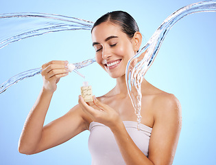 Image showing Happy woman, dropper and water splash for skincare serum, product or hygiene against blue studio background. Calm female smile holding pipette for beauty cosmetics, essential oil or facial treatment