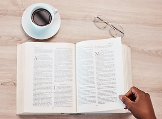 Image showing Hand, bible and a person reading in a coffee shop for religion, belief or faith in god and jesus. Education, learning and overhead with an adult in a cafe to study for spiritual knowledge in christ