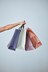 Image showing Hands, shopping bags and purchase in studio sale, discount or fashion against a gray background. Hand of shopper holding bag of buying gifts, present or luxury retail products or items on copy space