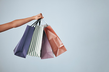 Image showing Hands, shopping bags and purchase on studio mockup for fashion, discount or sale against a gray background. Hand of shopper holding bag of gifts, present or luxury retail products on copy space