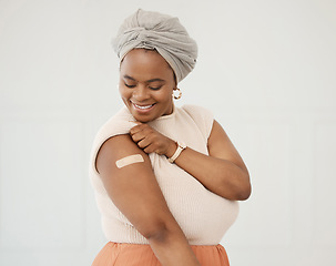 Image showing Covid, smile and black woman with plaster on arm in studio for injection on medical insurance. Happy African female on a white background with vaccine, safety compliance and medicine mockup space