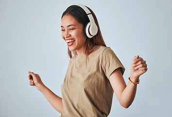 Image showing Happy woman, music headphones and dancing in studio with excited and positive mindset. Female model on white background to dance, fun and laughing with energy while listening to audio or radio