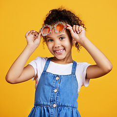 Image showing Girl child, studio portrait and sunglasses with smile, happiness and summer style by yellow background. Mixed race model, female kid and fashion frame on face with kids clothes, aesthetic and youth