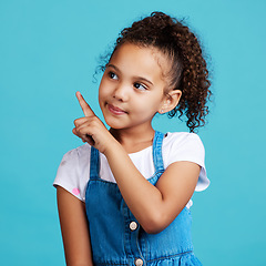 Image showing Girl child, thinking and point in studio with idea, looking and young with mind development by blue background. Female kid, pointing finger and focus with fashion, kids clothes or mindset by backdrop