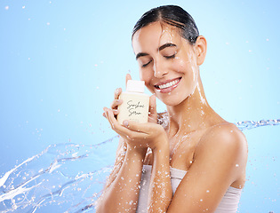 Image showing Happy woman, water splash and face with skincare serum, product or cream against blue studio background. Calm female smile holding moisturizer creme for beauty cosmetics or facial treatment on mockup