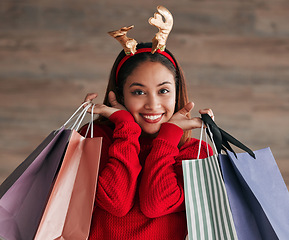 Image showing Bags, portrait and woman with a reindeer headband for a festive, xmas holiday celebration. Happy, smile and face of a female model shopping for gifts or presents with christmas accessories for event.