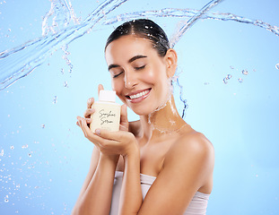 Image showing Happy woman, water splash and face with skincare moisturizer, product or cream against blue studio background. Calm female with smile holding lotion or creme for beauty cosmetics or facial treatment