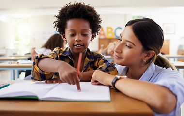 Image showing Teacher, learning and helping black kid in classroom for knowledge, studying or assessment. Question, development and boy or student with woman for education pointing in notebook in kindergarten.