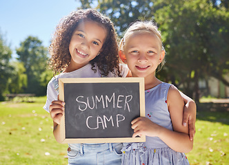 Image showing Summer camp, portrait or girls hugging in park together for fun bonding, development or playing in outdoors. Happy young best friends smiling or embracing on school holidays outside with board sign