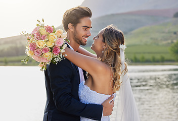 Image showing Wedding, couple hug and lake with a bride feeling love, care and support from marriage together. Nature, flower bouquet and young people with a happy smile from trust and commitment event by water