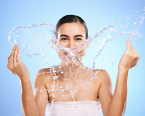 Image showing Water splash, portrait or girl with face wash for skincare, fresh body hygiene on blue background in studio. Female model with clean hands or wellness washing in beauty grooming for facial treatment