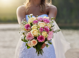 Image showing Closeup, bride and flower bouquet outdoor for celebration of commitment, ceremony and marriage. Woman, wedding and holding roses, spring flowers and floral blossom to celebrate love at elegant event