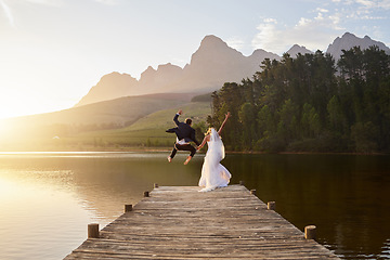 Image showing Wedding, bride and groom jumping in lake together with passion, love and romance. Crazy fun, marriage and happy couple on pier to celebrate romantic, loving relationship in nature and water from back