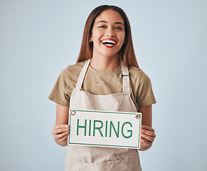 Image showing Happy woman, portrait and hiring sign for small business recruitment, career or job opportunity against a gray studio background. Female entrepreneur with apron holding billboard or poster for hire