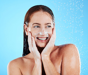 Image showing Woman in shower, smile with hygiene and water drops, soap and clean with excited face on blue background. Facial, hands and skincare with happy female washing, foam product and body care in studio