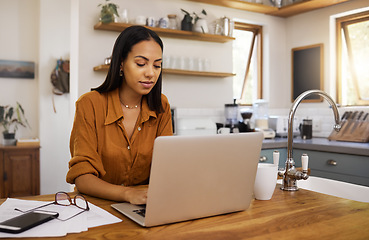 Image showing Home, remote work and business woman on laptop for research project, strategy and planning in kitchen. Freelancer, focus and girl with documents working online, typing email and busy on computer