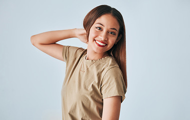 Image showing Portrait, smile and a woman in studio on a gray background feeling positive, carefree or cheerful. Face, happy and freedom with an attractive young female posing in clothes for contemporary fashion