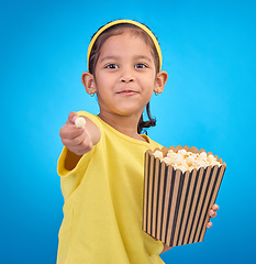 Image showing Popcorn, offer and smile with portrait of girl and giving snack to you for food, cinema and relax. Friendly, movie and film with child eating for streaming, subscription and tv on blue background